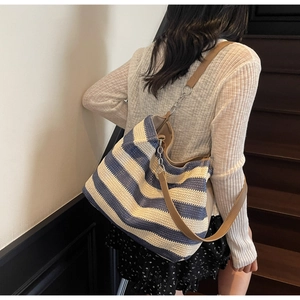 Detail of blue and white striped woven tote bag with brown faux leather shoulder straps