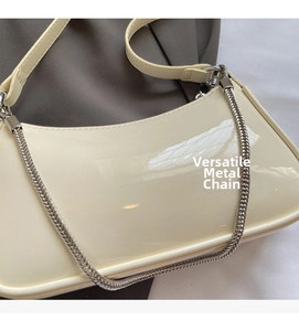 Détail montrant la texture en cuir verni brillant et la chaîne argentée du sac blanc