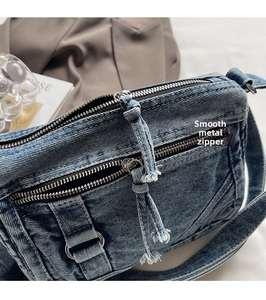 Close-up of premium denim crossbody bag featuring smooth metal zippers and denim pull tabs