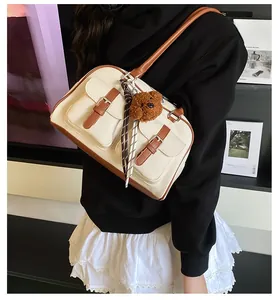 Detail of canvas and brown leather boston bag featuring side pocket and bear charm