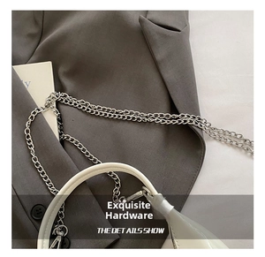 Detail showing glossy white handbag surface and polished silver metal chain hardware