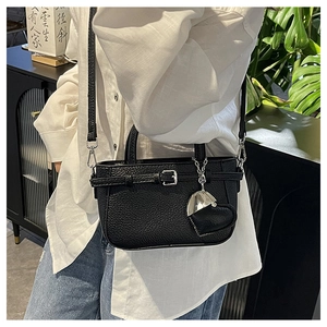 Detail of black lychee grain leather crossbody bag with silver heart charm and buckle