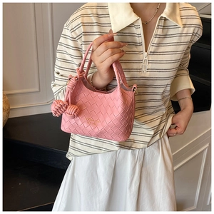 Gros plan détaillé du sac seau en cuir tressé rose avec pendentifs à nœuds déco