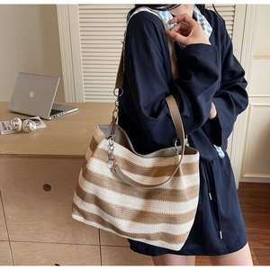 Détail de ce sac fourre-tout tissé à rayures avec bandoulière cuir et détails de chaîne