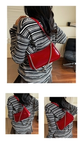 Détail du sac sous l'aisselle en cuir verni rouge avec fini brillant et chaîne argent