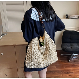 Detail of hand-woven cream hobo bag with hollow texture and decorative wooden beads