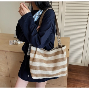Détail du sac cabas tissé rayé avec anses en cuir marron et maillons de chaîne argentés