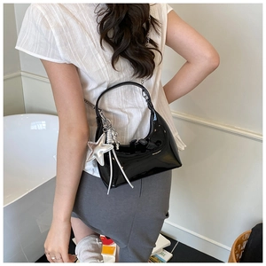 Detail of glossy black patent leather crescent bag with star pendant and silver chain