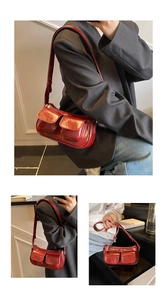 Detail view of red glossy underarm bag with double pockets and adjustable shoulder strap