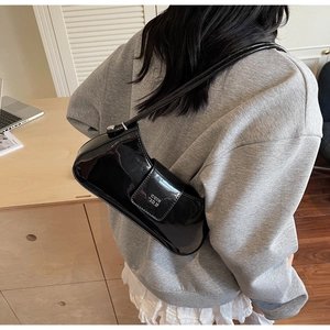 Vue détaillée d'un sac d'épaule en cuir verni noir brillant avec logo métallique