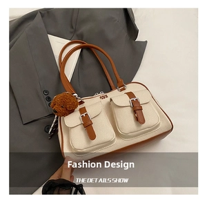 Detail of beige canvas shoulder bag with brown leather trim and two front buckle pockets