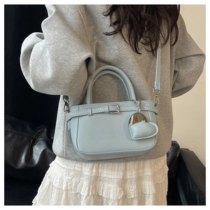 Model wearing a light blue litchi pattern handbag with a cute heart charm