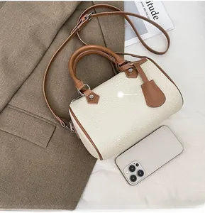 Size comparison of a compact Boston bag and an iPhone 12 on a brown blazer backdrop