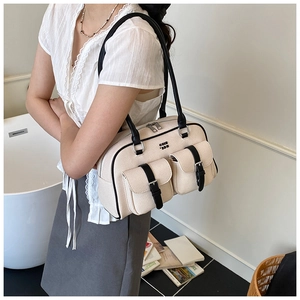 Close-up of stylish cream canvas shoulder bag with black strap and double front pockets