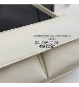 Close-up of cream crossbody bag featuring dual front pockets and Paris embossed detail
