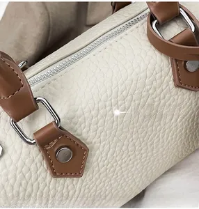 Close-up of off-white pebbled leather texture with silver hardware on Boston bag