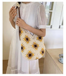 Detail of hand-crocheted sunflower patterns on a beige knit hobo shoulder bag