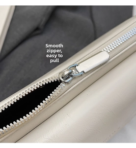 Detailed macro view of high-quality smooth silver metal zipper on minimalist cream handbag