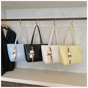Détail de quatre sacs fourre-tout à motif crocodile en diverses couleurs avec breloques