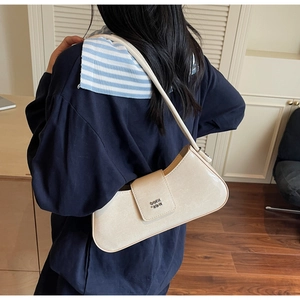 Détail d'un sac baguette beige minimaliste avec texture cuir et logo en métal poli