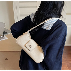 Détail du sac baguette crème avec logo métallique sur le rabat en cuir souple