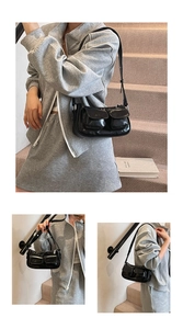 Detail of black glossy Y2K underarm bag featuring multiple pockets and adjustable strap