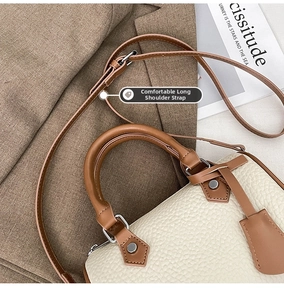 Close-up of pebble leather texture and brown handle on a stylish Boston handbag