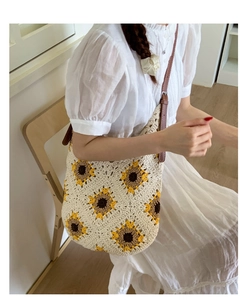 Close-up of knitted sunflower pattern on beige cotton bag with leather shoulder strap