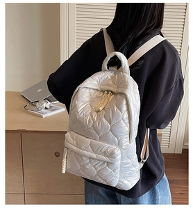 Detail of heart-quilted down-padded backpack in pearl white with braided zipper pulls