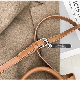 Detail of adjustable shoulder strap and silver metal buckle on brown leather bag