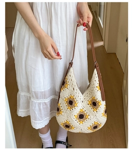 Detail of hand-crocheted cream tote bag featuring yellow sunflower motifs and brown leather strap