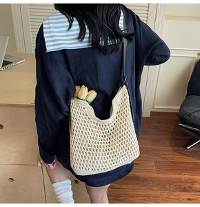 Close-up of cream crochet knit shoulder bag with leather strap and tulip detail