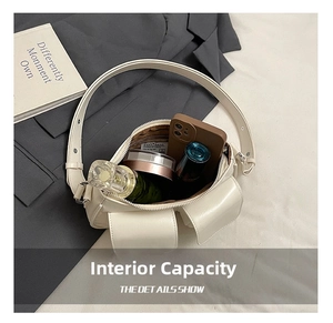 Interior capacity display of a cream leather shoulder bag with phone and cosmetics