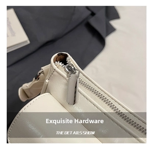 Detail of silver rectangular metal zipper on white leather shoulder bag with dark lining