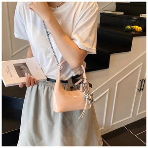 Detail of light pink patent leather bucket bag with silver chain and star charm accessory