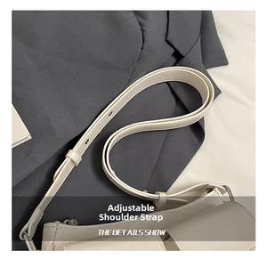 Close-up of beige leather shoulder bag with adjustable strap and metal grommet details