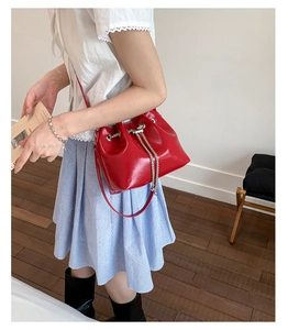Mannequin portant un sac seau en cuir rouge avec cordon de serrage en chaîne métal