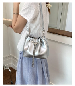Detail view of silver bucket bag featuring metallic PU texture and chain strap