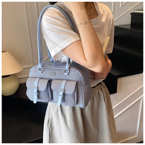 Detail of light blue denim Boston bag with dual buckle pockets and silver hardware