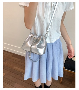 Detail of silver bucket bag showing metallic texture and drawstring chain closure