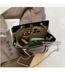 Interior view of black bucket bag showing spacious storage with chain strap and phone