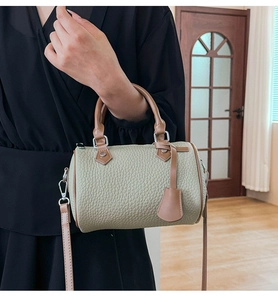 Detail view of green pebbled leather Boston bag with brown handles and a long shoulder strap