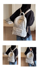 Detail of white quilted puffer backpack with soft padded texture and knot zipper puller