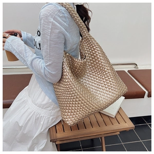 Close-up of golden woven hobo bag with wide shoulder strap and textured metallic finish