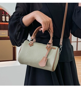Close-up of green lychee leather Boston bag with brown handles and premium metal hardware