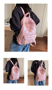 Close-up of pink quilted backpack with shiny metallic finish and woven zipper details