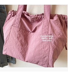 Pink drawstring tote bag featuring soft pleated texture and convenient front pocket