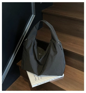 Detail of minimalist black large tote bag with wrinkled texture on wooden stairs