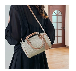 Close-up of contrast pebble leather Boston bag with adjustable strap on a model