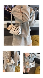 Close-up of white polka dot shoulder bag with cute brown plush bear charm and zipper